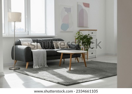Stylish living room with gray couch, white coffee table and lamp. Interior design