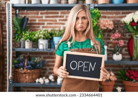 Young woman working at florist holding open sign depressed and worry for distress, crying angry and afraid. sad expression. 