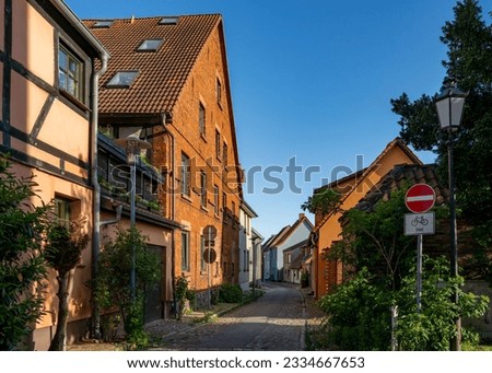 scenic alley with historic houses near the city gate in the small town Barth in the district Vorpommern-Rügen, Germany - the sky is blue, the sun is shining (translation: "frei" means "free") 