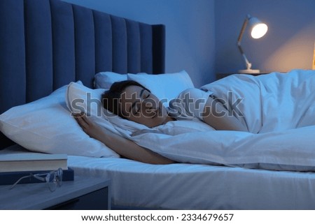 Beautiful young woman sleeping in bed at night Royalty-Free Stock Photo #2334679657