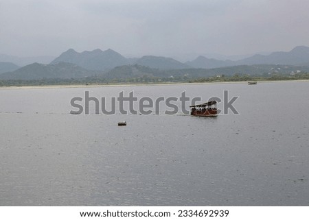 A captivating long shot captures the beauty of a solitary boat serenely gliding across the shimmering expanse of the tranquil lake, surrounded by breathtaking natural scenery. Royalty-Free Stock Photo #2334692939