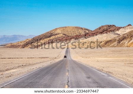A paved road or highway in the sunny desert leading to the horizon, Death Valley National Park, California, USA