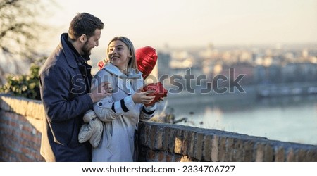 Portrait of a couple in love in an embrace. She is surprised by the gift and flowers. Royalty-Free Stock Photo #2334706727