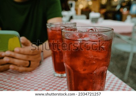 A closeup shot of two glasses with red iced drinks on a cafe table