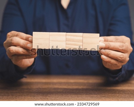 Business people hold four blank wooden cubes while sitting at the table. Close-up photo