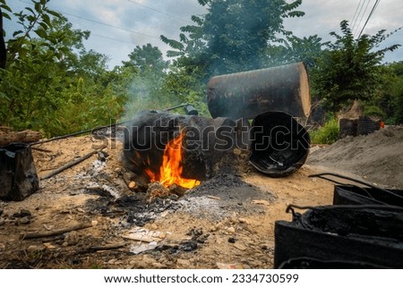 Black smoke coming out of burning coal tar barrels. This liquified coal tar is commonly used for constructing asphalt roads in India. Royalty-Free Stock Photo #2334730599