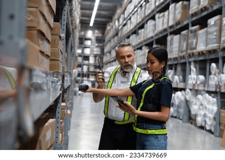 Warehouse manager coaching new employee to find  shipment from online inventory system and using scanner to scan barcode to check real time stock balancing. Online stock application for worker to use Royalty-Free Stock Photo #2334739669