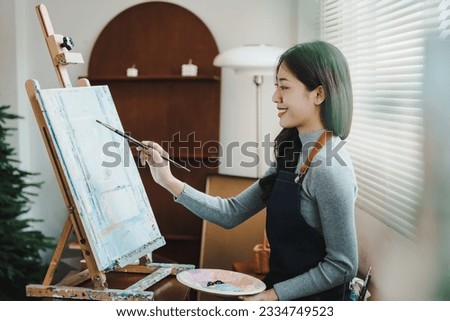 Female artist painting on canvas with brush Young painter working on the floor of her art studio creative young woman painting with oil paints creative concept