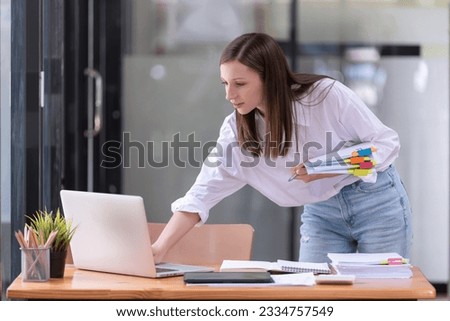 Businesswomen standing working with a laptop and holding documents in the office. Business's casual and successful concept