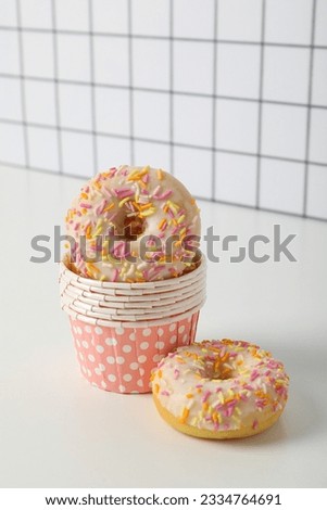 Donuts in paper cups on white table, on white background