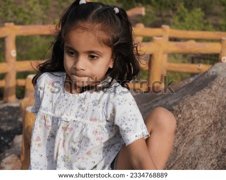 Cute little girl standing near wooden wall.Background blur with selective focus cear portrait photo.Different hand style and beautiful face in front of camera.