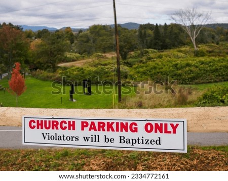 Funny sign outside a church in Stowe, Vermont, USA, with mountains in the background "Church parking only violators will be baptized"