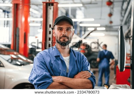 Standing with arms crossed. Auto mechanic working in garage. Repair service. Royalty-Free Stock Photo #2334780073