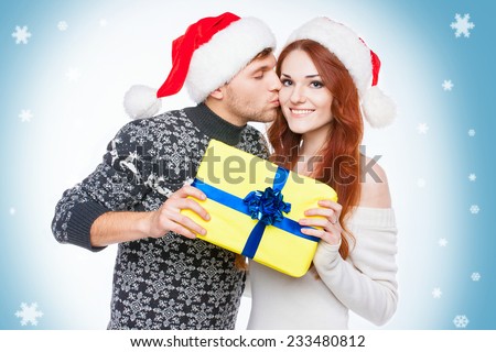 Happy couple with Christmas present over decorated blue background. 