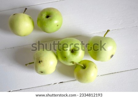 Sick apples from an organic farm. Apples without pesticide treatment. Healthy, but wormy apples. yellow-green apples on a white table. Royalty-Free Stock Photo #2334812193