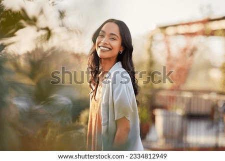 Young latin woman in casual clothing in the garden looking at camera, during early morning. Portrait of healthy mexican girl enjoying nature during sunset. Mindful multiethnic woman enjoy morning. Royalty-Free Stock Photo #2334812949