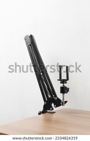A vertical closeup shot of a black mic holder attached to the wooden table