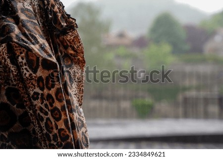 closed and wet umbrella with leopard print and background rain in the town in the winter