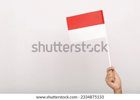 hands waving the red and white flag as a symbol of the Indonesian flag and copy space Isolated on gray background. indonesia independence day