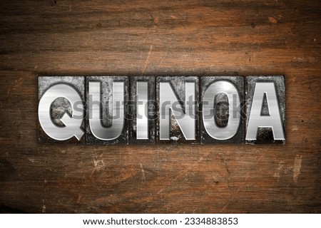 The word -Quinoa- written in vintage metal letterpress type on an aged wooden background.