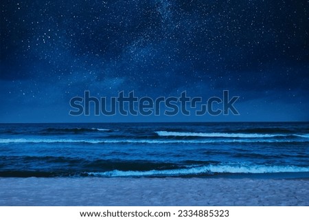 Sea waves rolling onto sandy beach under starry sky at night Royalty-Free Stock Photo #2334885323
