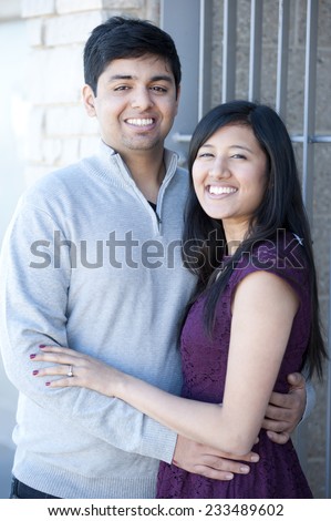 A young and happy Indian couple on a metal steel gray background on a sunny day.