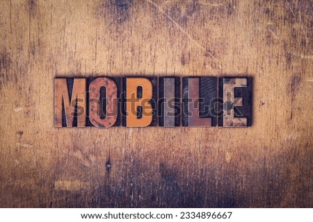 The word -Mobile- written in dirty vintage letterpress type on a aged wooden background.