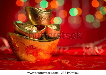 Chinese new year festival decorations, gold ingots on red glitter background.Copy space on side.