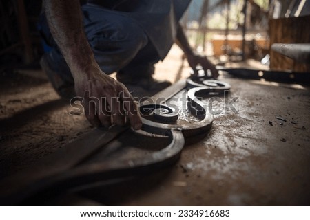 Close up of a blacksmith's hands checking the measurements of a grating in his workshop. Blacksmith concept. Royalty-Free Stock Photo #2334916683