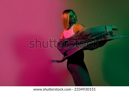 Photo of pretty adorable lady wear denim jacket dancing have fun empty space isolated green pink gradient color background