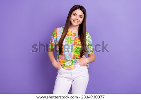 Photo of positive cute girl long hairstyle dressed flower print t-shirt standing arms in pockets isolated on violet color background