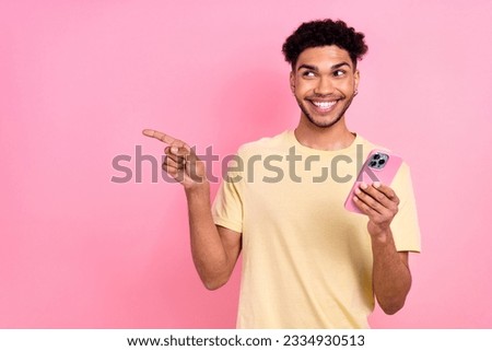 Portrait of funny man with afro hair earrings stubble hold smartphone directing look empty space isolated on pink color background