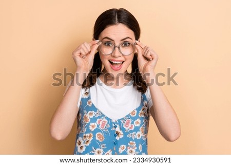 Photo of impressed funky carefree girl with curly ponytails wear blue overall touching glasses isolated on pastel color background