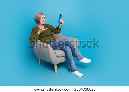 Full body size photo of retired blogging retired woman wear khaki video call communicating phone chair isolated on blue color background