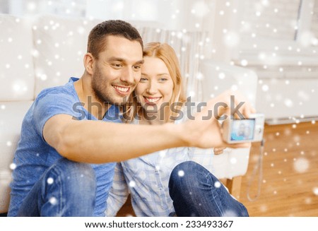love, family, technology and people concept - smiling couple taking selfie with digital camera at home