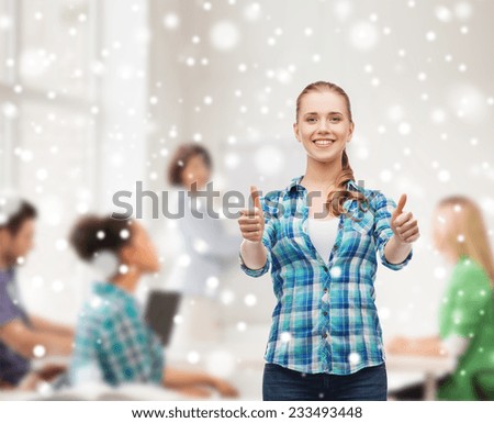 gesture, education, school and people concept - smiling student girl showing thumbs up over classroom and snow background