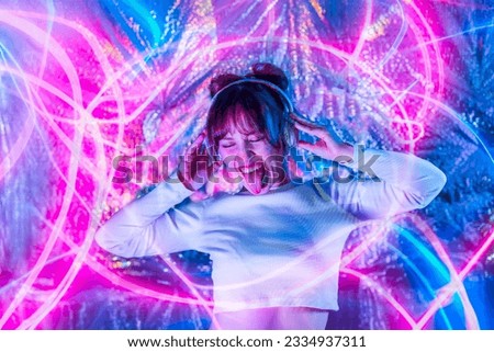 Portrait of emotional woman with closed eyes and tongue out in white clothes and headphones dancing in neon lights. Dj, Music lover. White dress code party. Silent disco. Having fun. Selective focus. Royalty-Free Stock Photo #2334937311