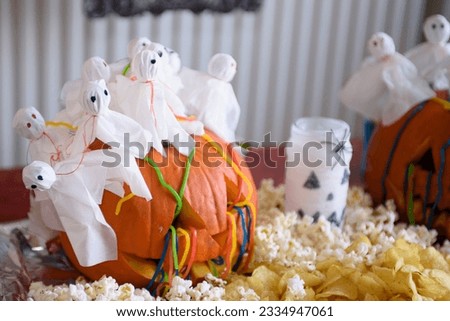 Halloween table decoration. The pumpkin is decorated with napkins in the form of ghosts. Halloween food for kids.
