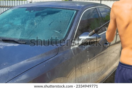 A man washes his car on the street. Selective focus. Nature.