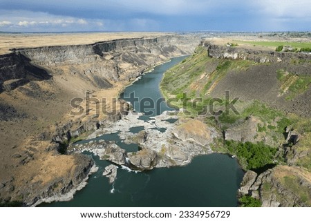 Aerial view of the Snake River canyon with the snake river and surrounding green grassland. Shot near the Perrine Memorial Bridge in Twin Falls, Idaho state, USA.