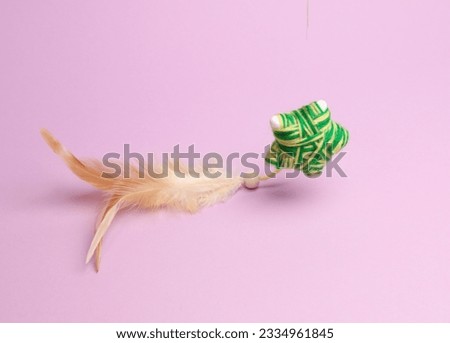 Cat toy with feather soaring on pink background