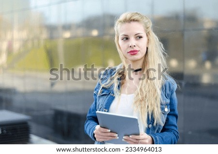 happy blonde student woman with tablet in a reflection wall