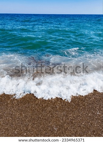 Beautiful sea background with pebble beach and blue waves with sea foam.