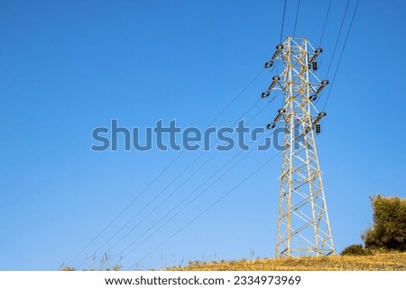 A support of a high-voltage electric line on a background of a bright dark blue autumn field.