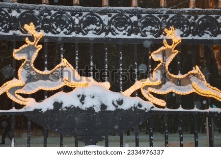 Silhouettes of Christmas deer on the fence. Outdoor shimmering festive Christmas decoration, beautiful decoration of the entrance, driveway.