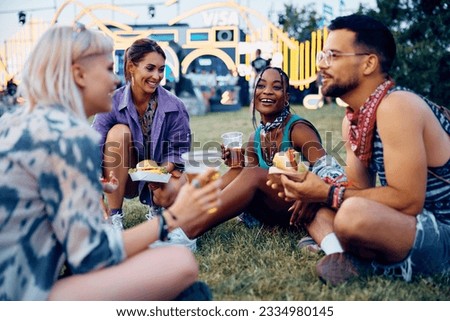 Happy friends talking while drinking beer and eating hamburgers during summer music festival. Royalty-Free Stock Photo #2334980145