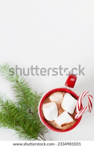 close-up of cup with hot cocoa, marshmallows and candy canes with christmas tree sprig