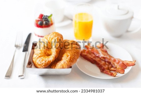delicious breakfast with fresh croissants, bacon, orange juice and granola yogurt served in hotel or at home
