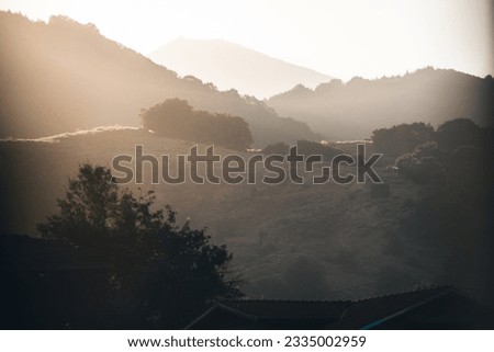 Beautiful sunset over the hills with a lot of haze and muted tones. Royalty-Free Stock Photo #2335002959