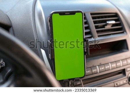 Mobile phone on the car air vent.Blank with green screen.Mock up smart phone in car. High quality photo